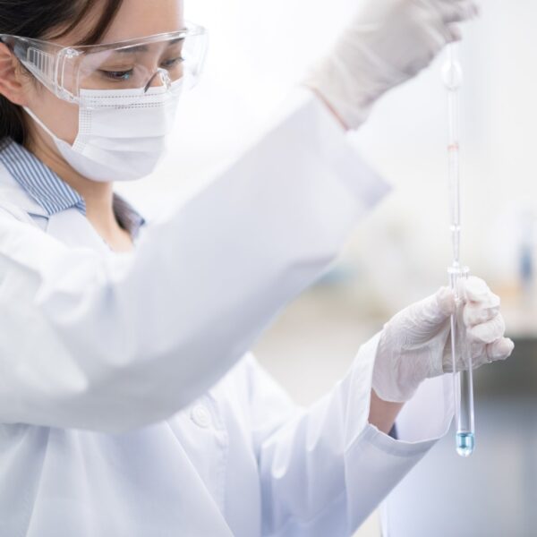 Lab worker dropping liquid in to a container.